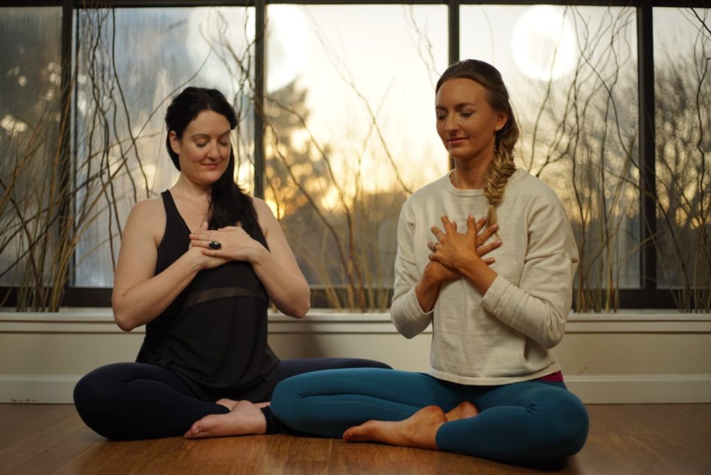 women holding hands to heart in meditation
