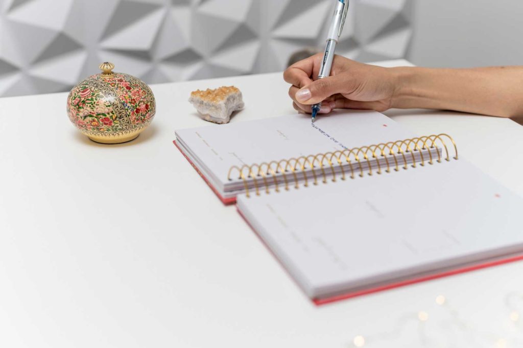 A woman's hand writing words in a journal