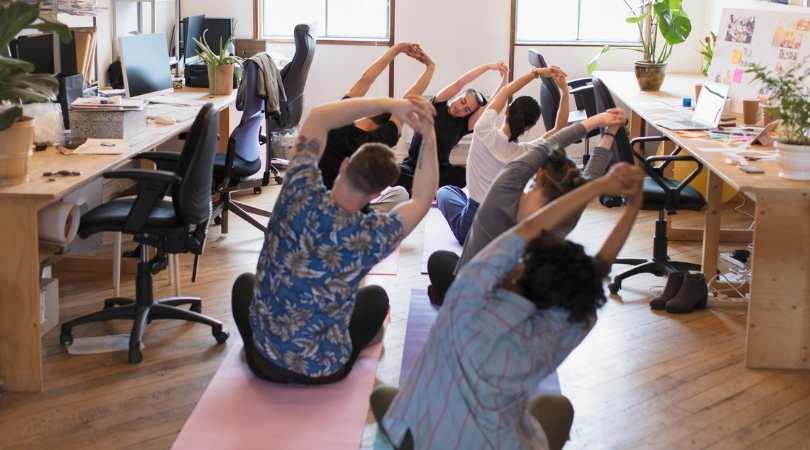 corporate yoga students in office stretching