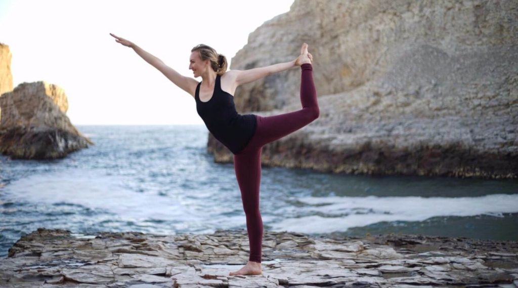 woman practicing yoga outdoors with dancer's pose