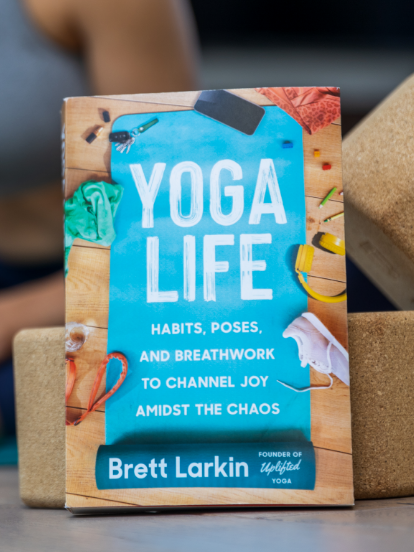 The Yoga Life book, written by Brett Larkin, propped up on two yoga blocks.