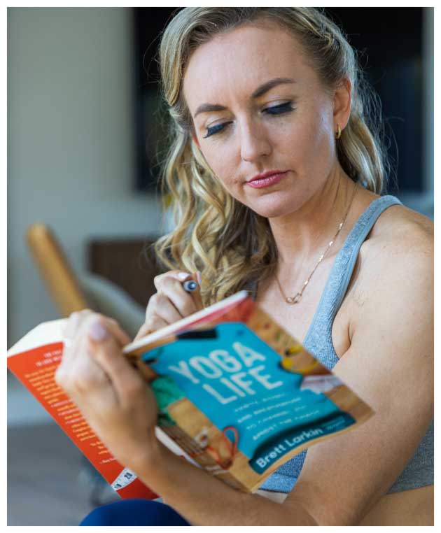 Brett Larkin reading her book, Yoga Life, and thinking through one of the several personal quizzes inside the text.