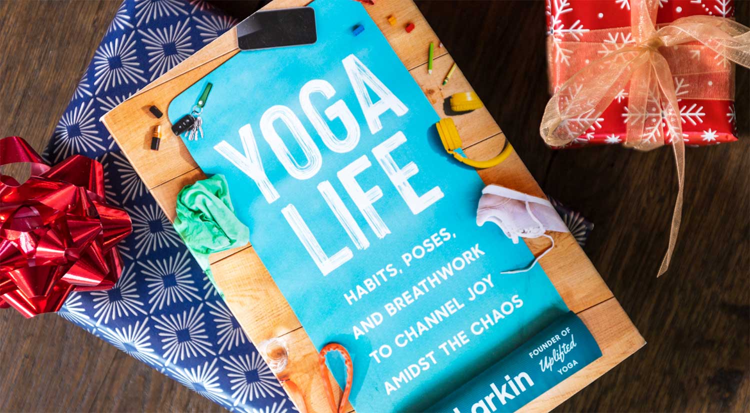 Brett Larkin's book, Yoga Life, surrounded by holiday themes gifts in Christmas wrapping paper.