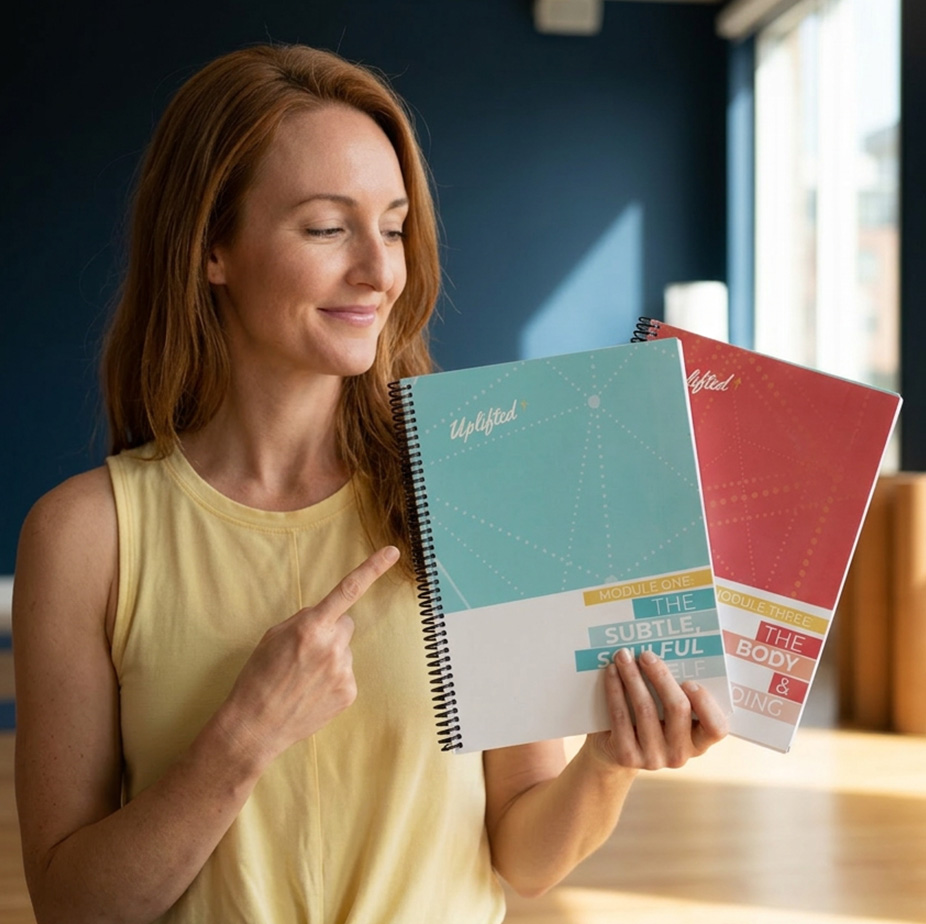 Student holding Uplifted 300-Hour Yoga Teacher Training manuals for an advanced online Yoga Alliance-approved certification.