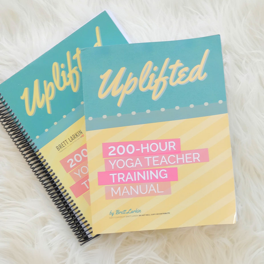 Uplifted 200-Hour Yoga Teacher Training manual by Brett Larkin displayed on a white background, featuring the course workbook used in online yoga teacher certification.