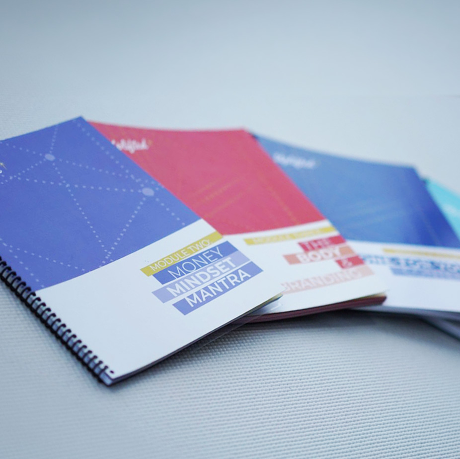 Printed Uplifted yoga teacher training workbooks featuring business and mindset modules used in advanced yoga certification coursework.